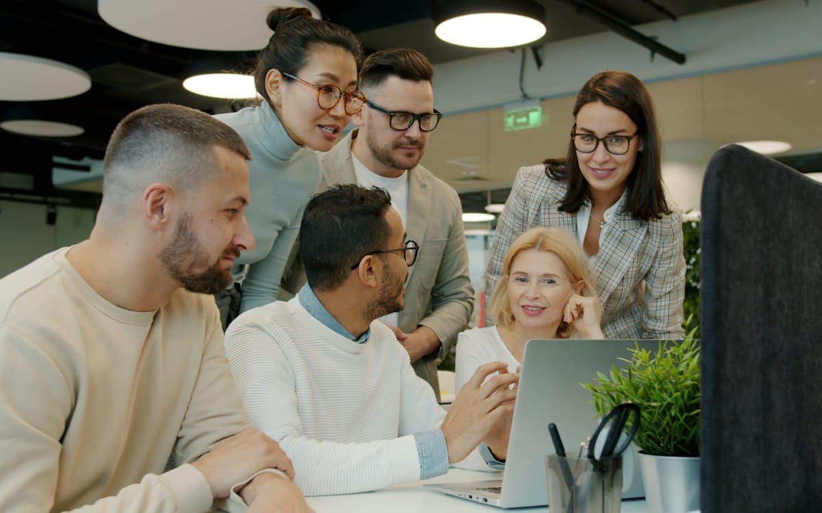 A team gathered around a laptop in a bright office